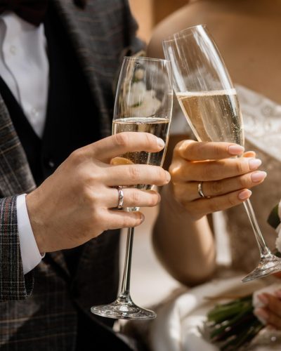Front view of wedding couple's hands with champagne glasses and wedding bouquet